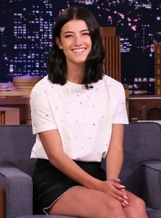 a woman sitting on top of a blue couch in front of a tv screen with her legs crossed