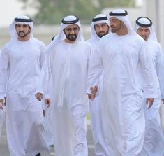 several men in white are walking down the street