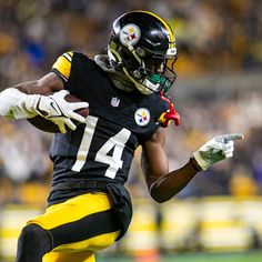 a football player running with the ball in his hand and holding it up to his chest