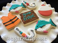 decorated cookies are arranged on a plate with fishing related items in the shape of fish hooks