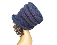 a woman's hand holding up a crocheted hat on top of her head