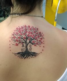 a woman's back with a tree tattoo on her left shoulder and chinese characters underneath it