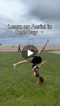 a woman doing a handstand on the grass in front of an open field