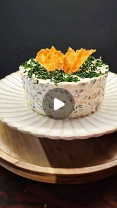 a white plate topped with food on top of a wooden table next to a black wall