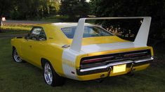 a yellow and white muscle car parked in the grass