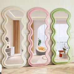 there are three mirrors on the wall, one is shaped like wavy lines and the other has an oval shape