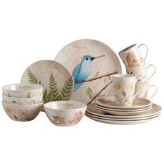 a blue bird sitting on top of a plate next to cups and saucers