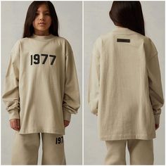 Brand New With Tags Attached Kids Size Xxl (14/16) Color : Wheat The Essentials Fear Of God Kids "1977" Wheat Long Sleeve T-Shirt Features An Oversized Fit, A Mock Neckline, Long Sleeves, A Bold "1977" Graphic On The Front And A Rubber Brand Label At The Upper Back. Solid Color Tee Long Sleeves Mock Neckline 1977 Graphics Rubber Brand Label Oversized Fit 100% Cotton Jersey Hand Wash, Flat Or Line Dry Unisex Long Sleeve Lounge Tops, Unisex Casual Long Sleeve Tops, Unisex Long Sleeve Loungewear Tops, Unisex Long Sleeve Tops For Loungewear, Casual Long Sleeve T-shirt, Unisex Long Sleeve T-shirt With Letter Print, Essentials Fear Of God, Oversized Long Sleeve Shirt, Brand Label