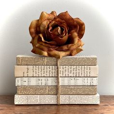 two books stacked on top of each other with a flower sitting on top of them