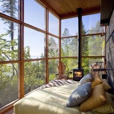 a bed with pillows on top of it in front of large windows and a wood burning stove