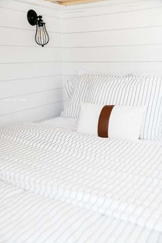 a bed with white and brown striped bedspread next to a light fixture on the wall