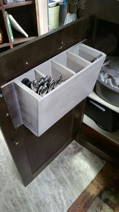 an open drawer in the middle of a kitchen counter with utensils inside it