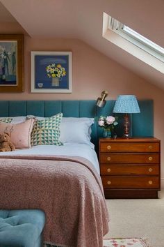 a bedroom with pink walls, blue bedding and a teddy bear on the dresser