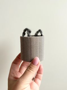 a person holding up a small box with two hair clips in it's center