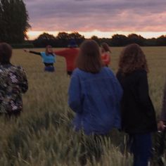 four people standing in a field watching the sun set