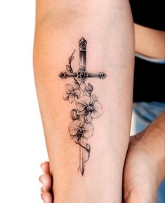 a cross and flowers tattoo on the arm