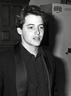 black and white photograph of a man in a suit standing next to a refrigerator freezer