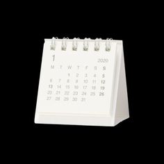 a white desk calendar sitting on top of a black surface with the date circled out