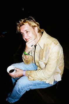 a man sitting on the ground holding a cup