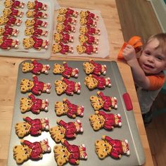 a little boy standing in front of some cookies on a pan with teddy bears cut out of them