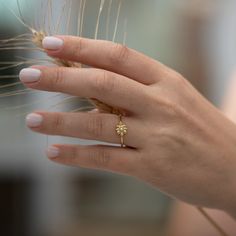 a woman's hand with a ring on it and a plant in the background