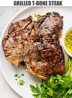 grilled t - bone steak on a white plate with green garnish