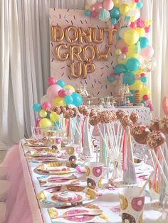 a table topped with lots of desserts and balloons in front of a sign that says donut grow up