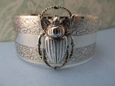 "Myelegantthings presents a gorgeous Scarab Beetles cuff.bracelet. I made these in 1970's for my jewelry line, \"Angelina Verbuni Designs\" 1 inch engraved cuff opens in back The scarab is about 1 inch. 18 K matt gold plating over brass All brass vintage findings. Chic! I have other bangles I've made also with bumble bees, panthers, butterflies and lions and lots of necklaces to match also. Available in silver or gold All USA made" Vintage Brass Cuff Jewelry, Silver Brass Cuff Jewelry, Silver Brass Cuff Bracelet For Wedding, Victorian Brass Silver Bracelets, Vintage Metal Cuff Bangle, Vintage Nickel Free Cuff Jewelry, Nickel-free Vintage Cuff Jewelry, Vintage Nickel-free Cuff Jewelry, Nickel-free Vintage Bangle As A Gift