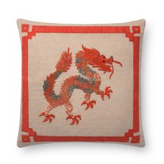 a red and beige pillow with an embroidered dragon on the front, sitting on a white surface