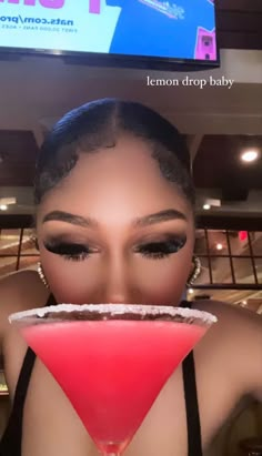 a woman is holding a martini in front of her face