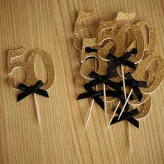 the number 50 is made out of cake sticks with black bows and glitter on them