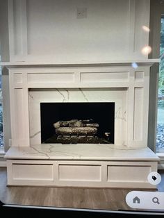 a white fireplace in a living room next to a window