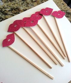 a bunch of wooden sticks with pink glitter on them sitting on top of a table