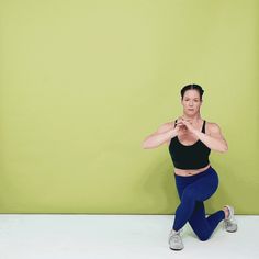 a woman is doing yoga in front of a green wall