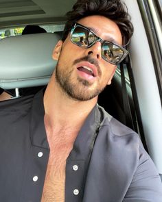 a man wearing sunglasses sitting in the back seat of a car