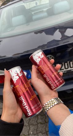 two cans of red bull energy drink in front of a car