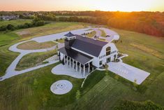 an aerial view of a large white house in the middle of a green field at sunset