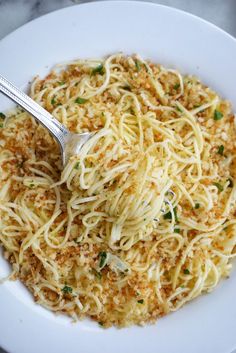 a white plate topped with spaghetti and parmesan cheese sauce next to a fork