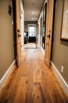 an empty hallway with wood floors and two doors leading to another room in the house