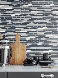 a kitchen counter topped with a coffee pot and cup next to a wooden cutting board