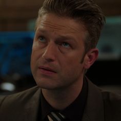 a man wearing a suit and tie looking off into the distance with an intense look on his face