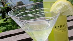 a glass filled with white wine next to a bottle on a wooden table near the water