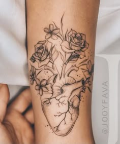 a woman's arm with flowers and a heart tattoo on it