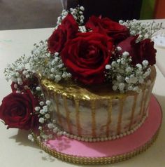 a cake decorated with red roses and baby's breath