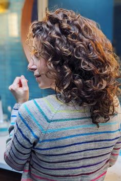 This attractive hairstyle shows beautifully shaped curls that flow nicely, having been cut into sections that naturally frame the face. The shorter pieces around the face add fullness and draw attention to the cheeks, improving the overall form of the haircut. The rich, varied colors of the hair match the - Click to see more of Curly Hair Trends in 2024: Embrace Your Curls with 30 Gorgeous Face Framing Layers and follow us for more hairstyle ideas. // Photo Credit: Instagram @tanisfiberarts The Haircut