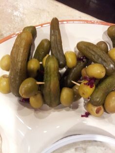 several pickles and olives on a plate with toothpicks sticking out of them