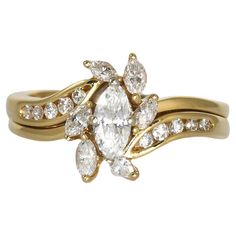 a yellow gold ring with an oval cut diamond surrounded by smaller round diamonds on each band