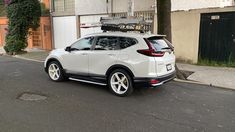 a white car parked on the side of a street next to a tall building and trees