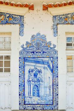 an ornate blue and white tile mural on the side of a building with two doors