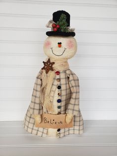 a stuffed snowman wearing a top hat and coat with a name tag on it